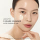 Enlarge image of Close-up of model with a cream swatch on her cheek and text reading &amp;#39;LOOK UP TO 5 YEARS YOUNGER AFTER 12 WEEKS OF USE&amp;#39;.